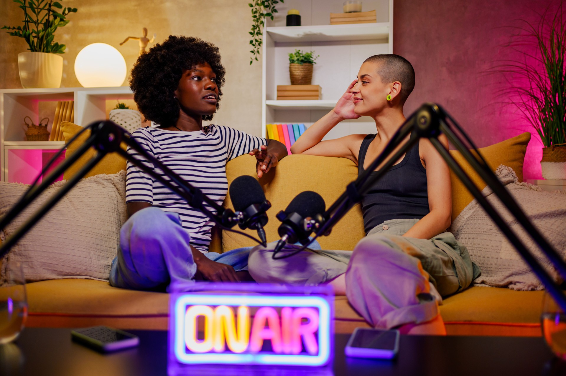 Couple of diverse women recording episode of internet podcast in a cozy studio